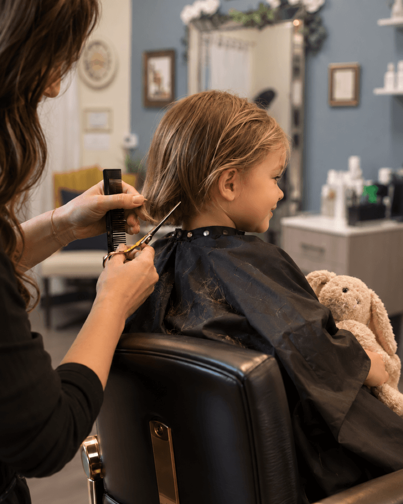 Young child getting a haircut in a salon chair