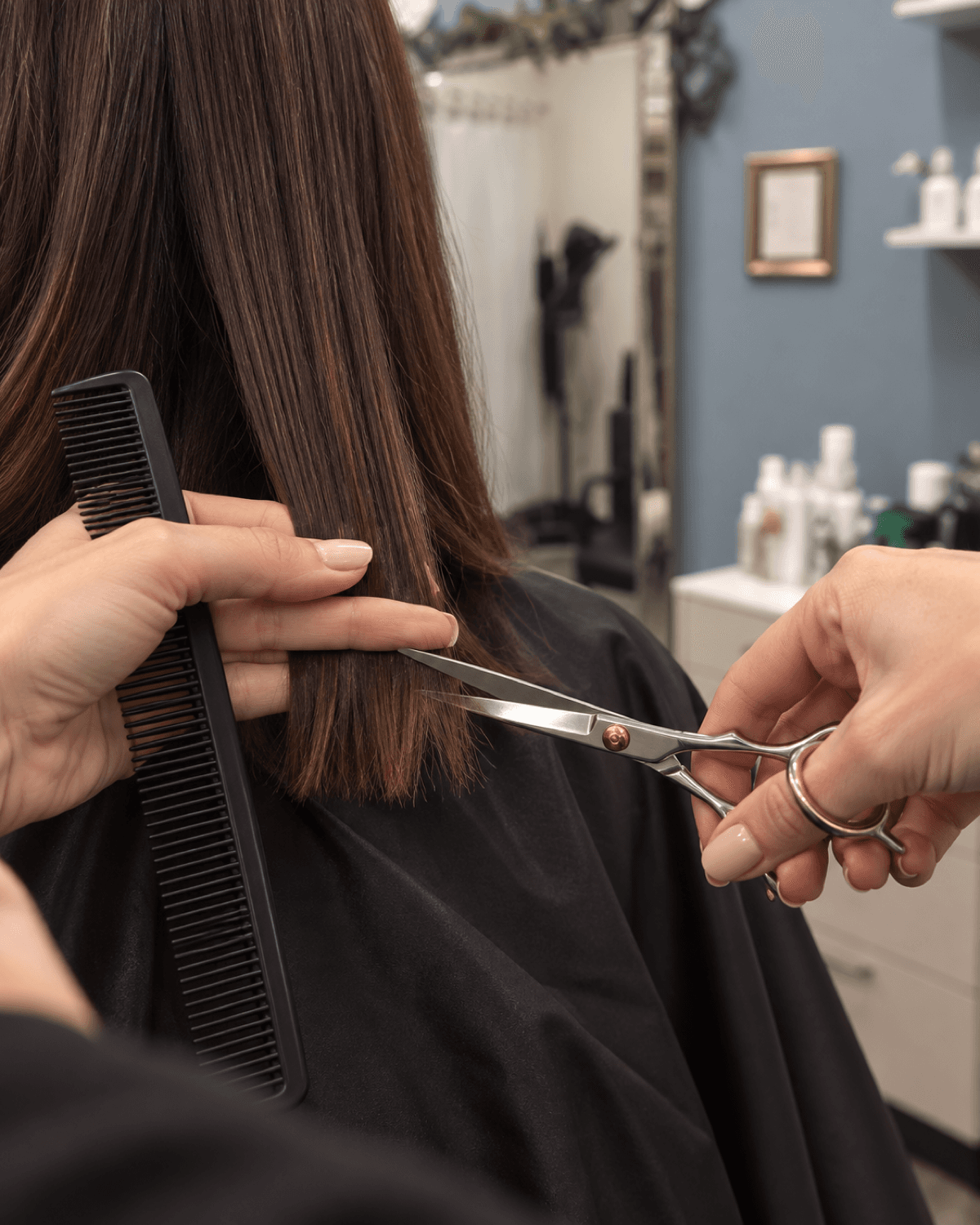Stylist's hands trimming the ends of a client's hair with shears
