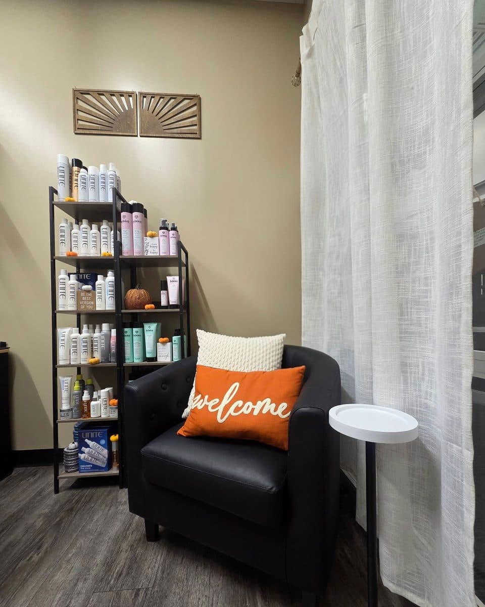 Welcome seating area with a leather chair and retail shelves at Metropolitan Hair Boutique